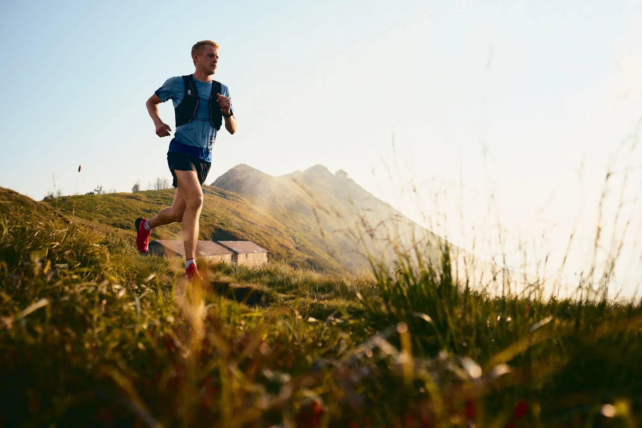 Runner in red shoes and blue top, mid-stride in alpine landscape of Ascona-Locarno.