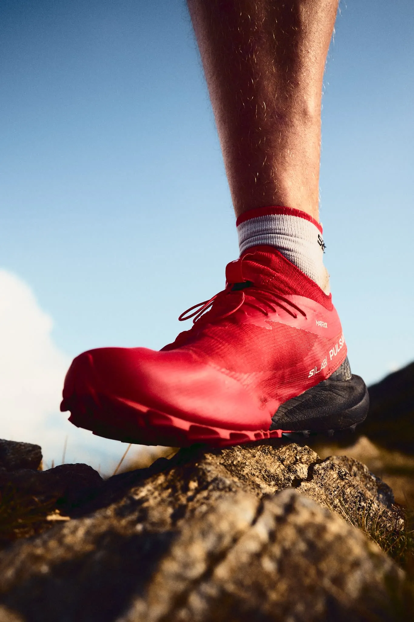 Close-up of red Salomon trail running shoe on rocky terrain