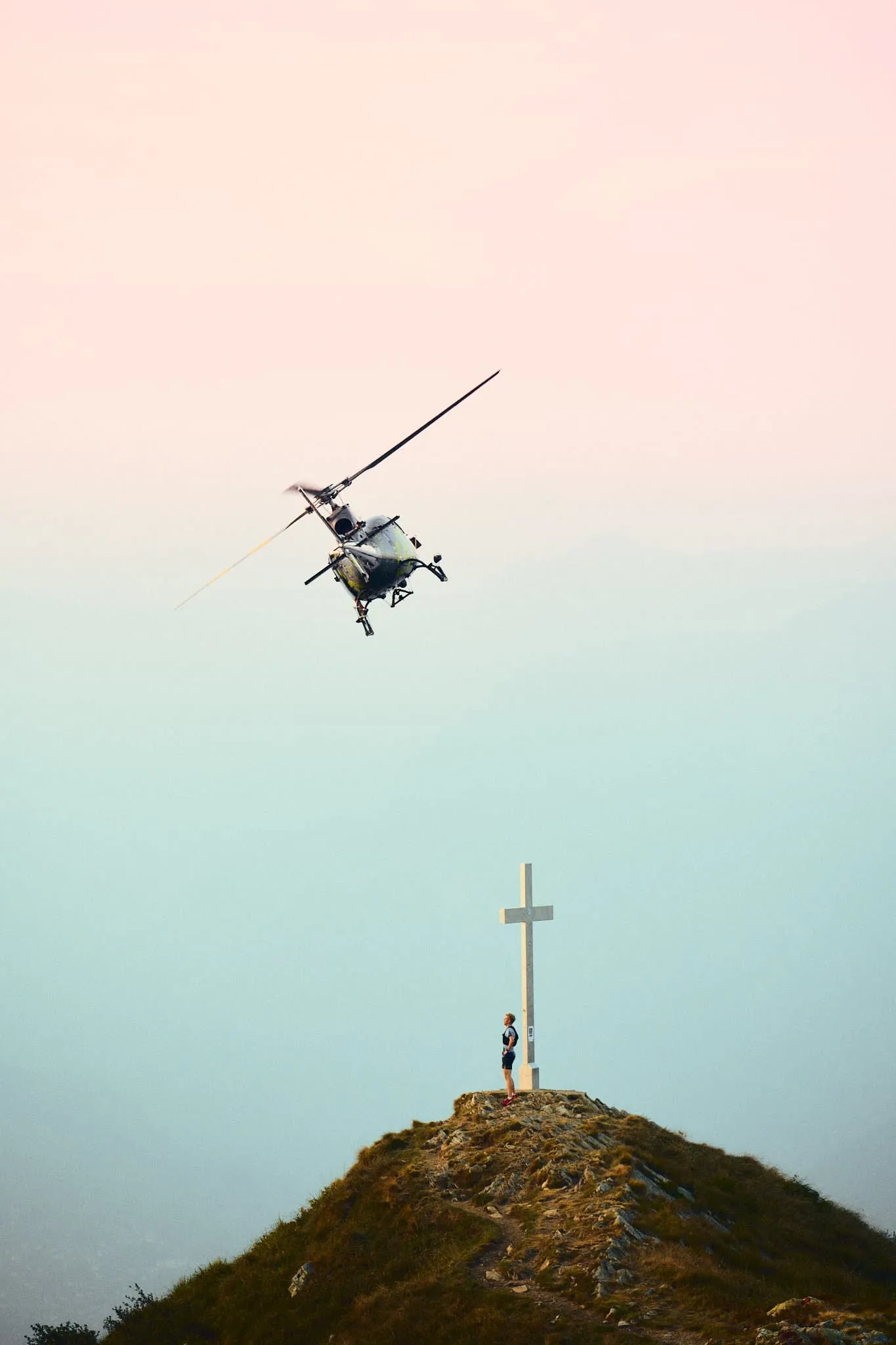 The narrative intensifies — a person stands reverently by the cross as a helicopter dramatically dips into frame. It’s cinematic and filled with tension and awe.